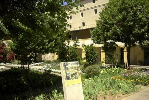 a sign in a garden in front of a building at Auberge de Jeunesse HI Arles in Arles