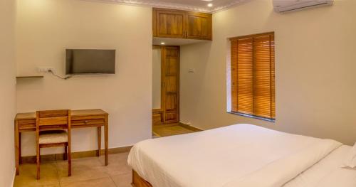 a bedroom with a bed and a desk and a television at Ekana Homes in Trivandrum