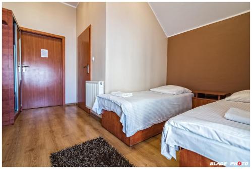 a small room with two beds and a door at Kompleks Noclegowy Warka in Warka