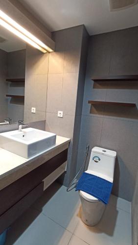 a bathroom with a sink and a toilet with a towel on it at Ruby Apartment #7 in Yogyakarta