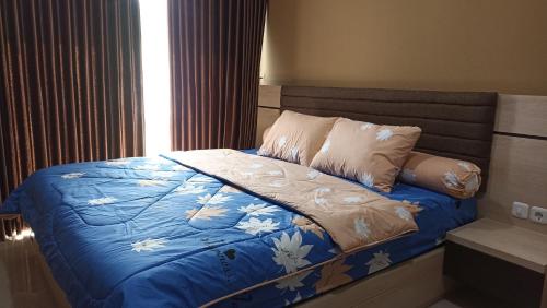 een slaapkamer met een bed met een blauw dekbed en kussens bij Ruby Apartment #7 in Kejayan