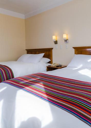 two beds in a hotel room with white sheets at Hotel de Turistas Huancayo - Hotel Asociado Casa Andina in Huancayo
