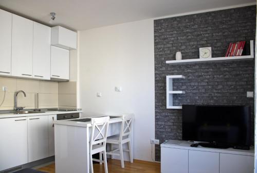 una cocina con armarios blancos y una pared de ladrillo en Studio Apartman Miljacka 13 Sarajevo, en Sarajevo