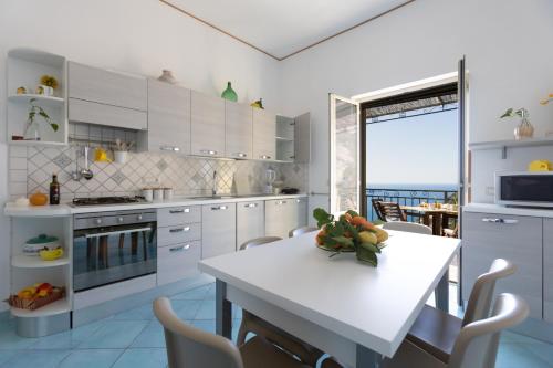 a kitchen with white cabinets and a white table and chairs at Casa la Perla in Positano