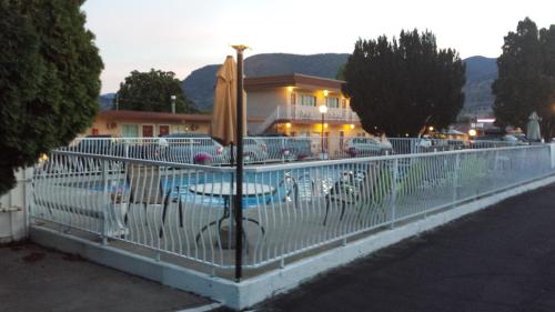a fence with a table and an umbrella next to a pool at Swiss Sunset Inn in Penticton