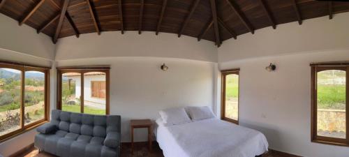 1 dormitorio con cama, sofá y ventanas en Ocarina Suites, en Villa de Leyva