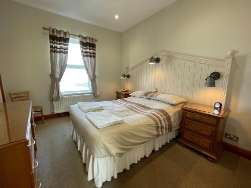a bedroom with a large bed and a window at Chandlers BnB in Seahouses