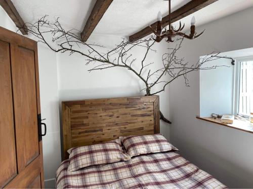 a bedroom with a bed with a branch on the wall at Lotte’s Cottage in Bideford