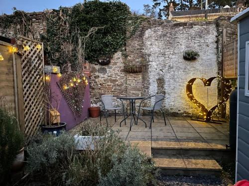 a patio with a table and chairs and a brick wall at Lotte’s Cottage in Bideford