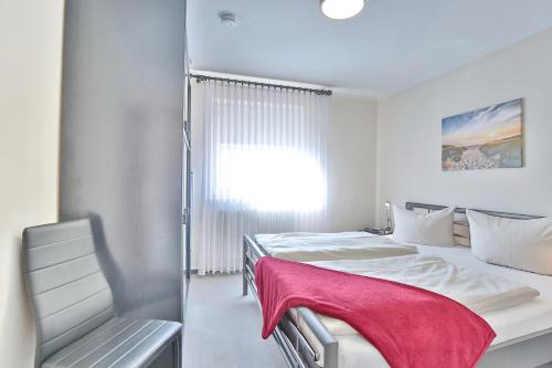 Un dormitorio blanco con 2 camas y una silla en Parkresidenz Parkresidenz Appartement 11, en Scharbeutz