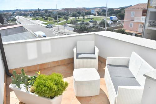 a balcony with white chairs and plants on a roof at Angelique Affittacamere in Santa Teresa Gallura