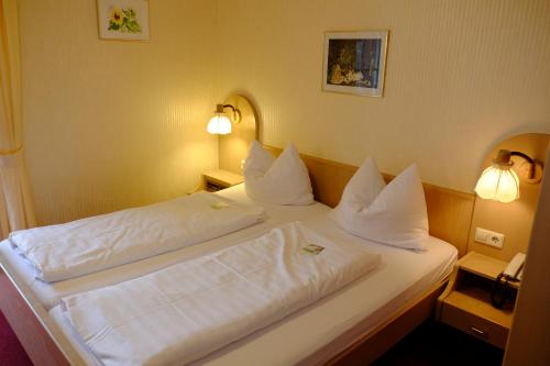 a bedroom with a bed with white sheets and pillows at Flair Hotel Schwanen in Bad Bellingen