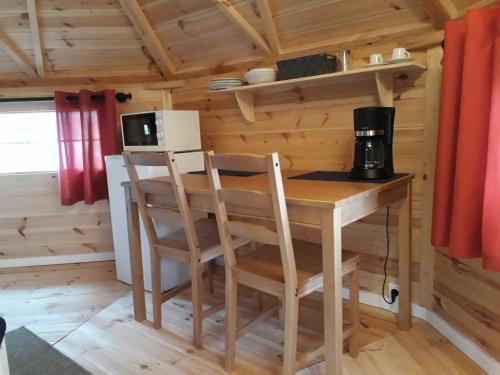 eine kleine Küche mit einem Tisch und Stühlen in einer Hütte in der Unterkunft Chambre KOTA Insolite in Attigny
