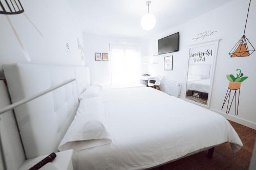 a white bedroom with a white bed and a window at Hostal Misericordia in León
