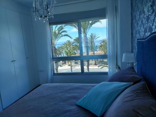 a bedroom with a bed and a window with palm trees at Meandyou Marazul Lamanga in La Manga del Mar Menor