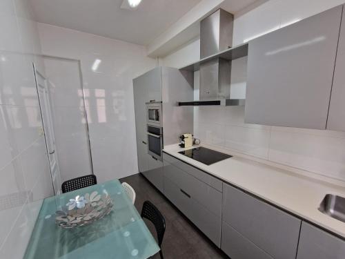 - une cuisine blanche avec une table et un comptoir dans l'établissement Amplio y céntrico piso con patio., à La Corogne