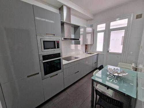 une cuisine avec des armoires blanches et un four à plaques de cuisson dans l'établissement Amplio y céntrico piso con patio., à La Corogne