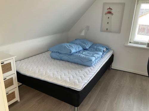 a bed with blue pillows on it in a room at Vesterhavsvej in Hvide Sande
