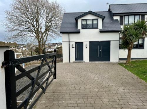 a house with a black and white garage at Orchard Lodge-Coastal Retreat, newly built hideaway with village views and private terrace in Saint Brides Major
