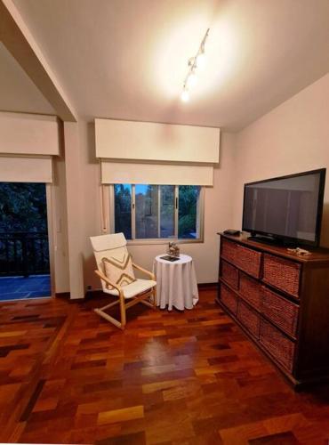 a living room with a tv and a chair and a table at Hermosa habitación en apartamento en Carrasco - Comparte Apartamento conmigo in Montevideo