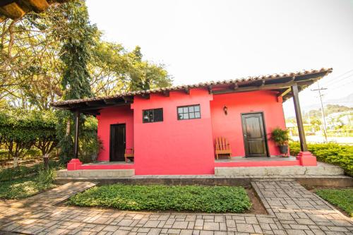 a red house with a porch and a patio at Hotel de Campo Villa de Ada in Gracias