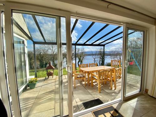 einen Wintergarten mit Glastüren und einem Tisch auf der Terrasse in der Unterkunft Shamrock Cottage in Aghnablaney