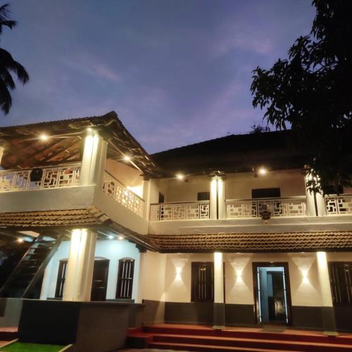 a large white house with a balcony at night at SuKun Heritage in Kannur