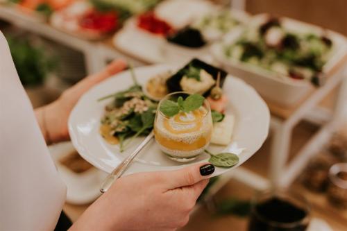 a person holding a plate of food with a drink at Hotel Dębowe Wzgórze Wellness & Spa in Jarnołtówek