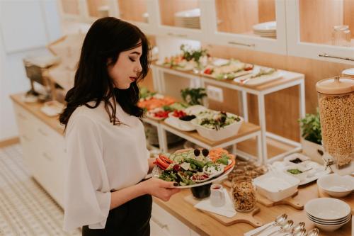 a woman standing in a kitchen holding a plate of food at Hotel Dębowe Wzgórze Wellness & Spa in Jarnołtówek