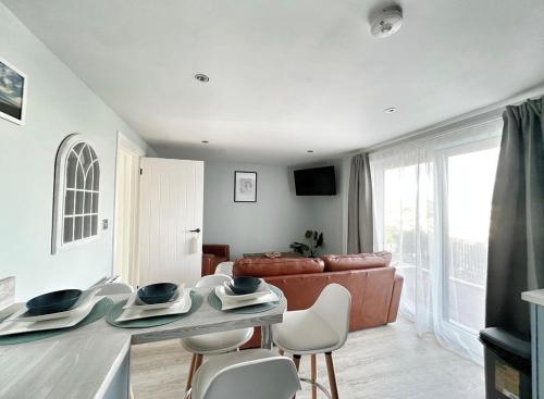 a living room with a couch and a table and chairs at Orchard Lodge-Coastal Retreat, newly built hideaway with village views and private terrace in Saint Brides Major