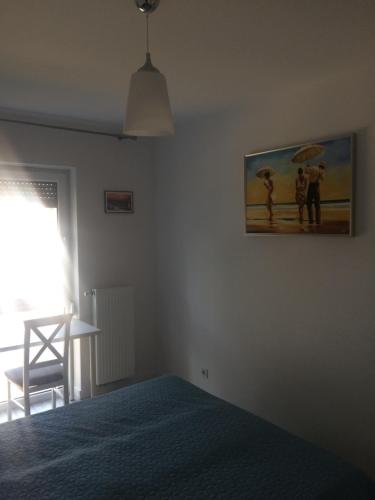 a bedroom with a bed and a painting on the wall at Apartament 44 Pogo in Pogorzelica
