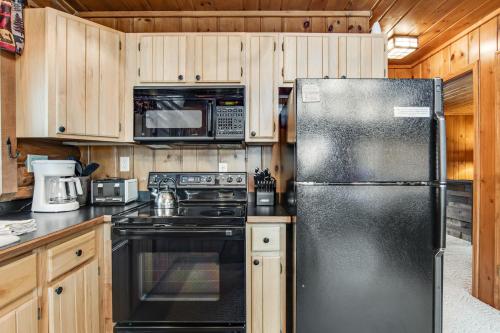 a kitchen with a black refrigerator and wooden cabinets at Annabelle Log Home in Presque Isle