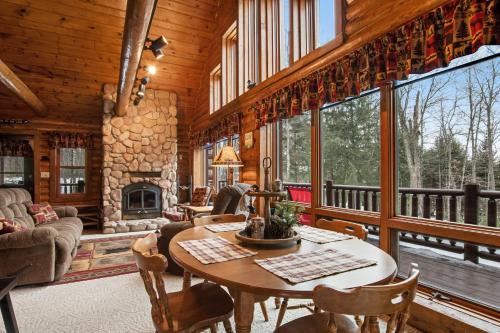 a living room with a table and a fireplace at Annabelle Log Home in Presque Isle
