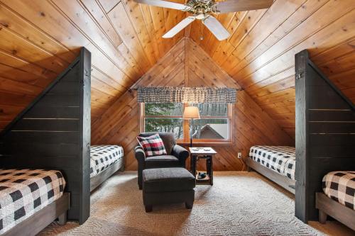 a bedroom with two beds and a chair in a attic at Annabelle Log Home in Presque Isle
