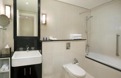 a white bathroom with a sink and a toilet at DAMAC Maison Canal Views in Dubai