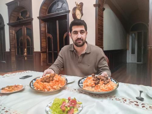 a man sitting at a table with three plates of food at May Weather Resort in Bukhara