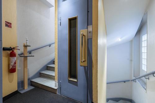 a hallway with a blue door and stairs with a fire extinguisher at Modern Waikiki Hotel in Cannes