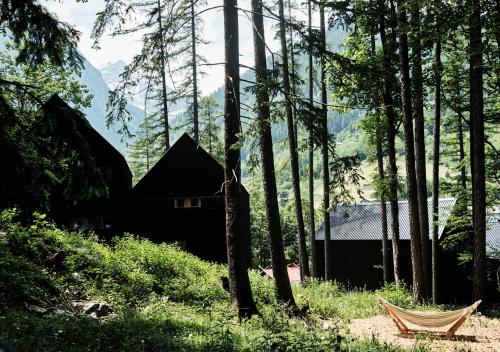 a house in the woods with a chair in the foreground at Älmele - Waldchalets Brandnertal in Brand