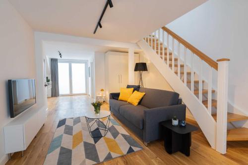 a living room with a couch and a staircase at LightHouse Whg 5 in Norderney