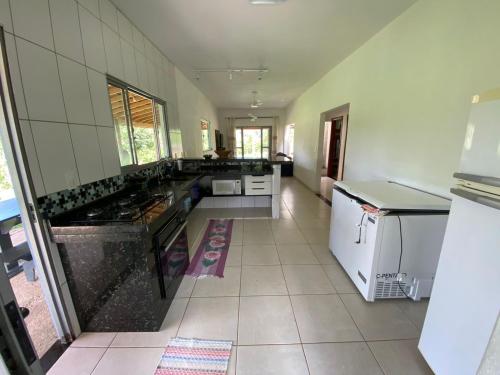 une grande cuisine avec comptoirs noirs et appareils blancs dans l'établissement Chácara Bertelli, à Socorro