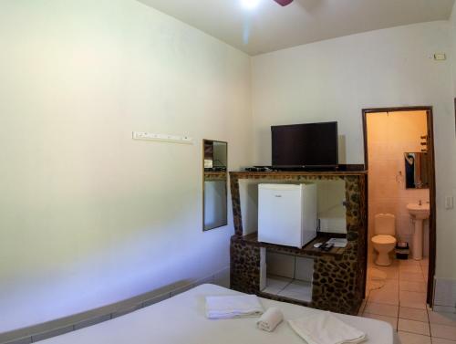 a room with a bed and a tv and a mirror at Pousada Casa de Pedra in Iporanga