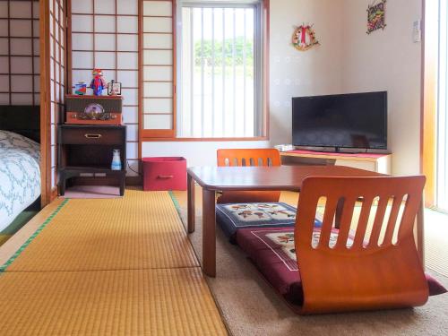 um quarto com uma mesa e cadeiras e uma televisão em Minshuku Itoman Bettei Goyukkuri em Itoman