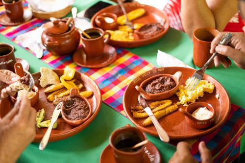 a group of people sitting at a table with plates of food at Hotel de Campo Villa de Ada in Gracias