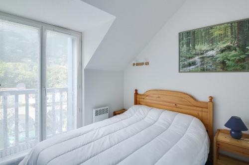Un dormitorio con una cama y una ventana grande. en l'orée du bois appartement t3, en Cauterets