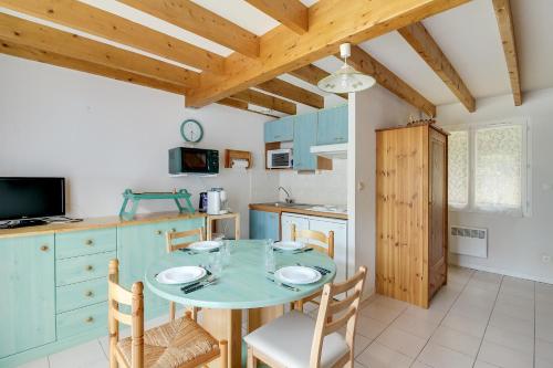 une cuisine avec une table et des chaises dans une pièce dans l'établissement l'orée du bois appartement t3, à Cauterets