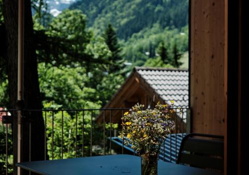 um vaso de flores sentado numa mesa na varanda em Älmele - Waldchalets Brandnertal em Brand