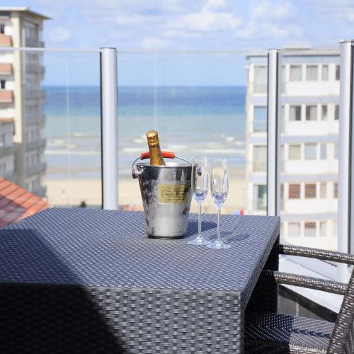 a table with a bucket and two wine glasses on a balcony at Casino Hotel in Koksijde