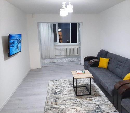 a living room with a couch and a table at Stylish 1-bedroom apartment near Atlas Mall & Ecobozor in Tashkent