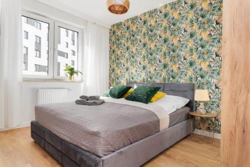 a bedroom with a bed with a floral wall at South4You Apartments in Wrocław