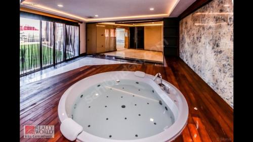a large bath tub in a room with wooden floors at ORIGINE RENTALS AN2 in Hurmaköy